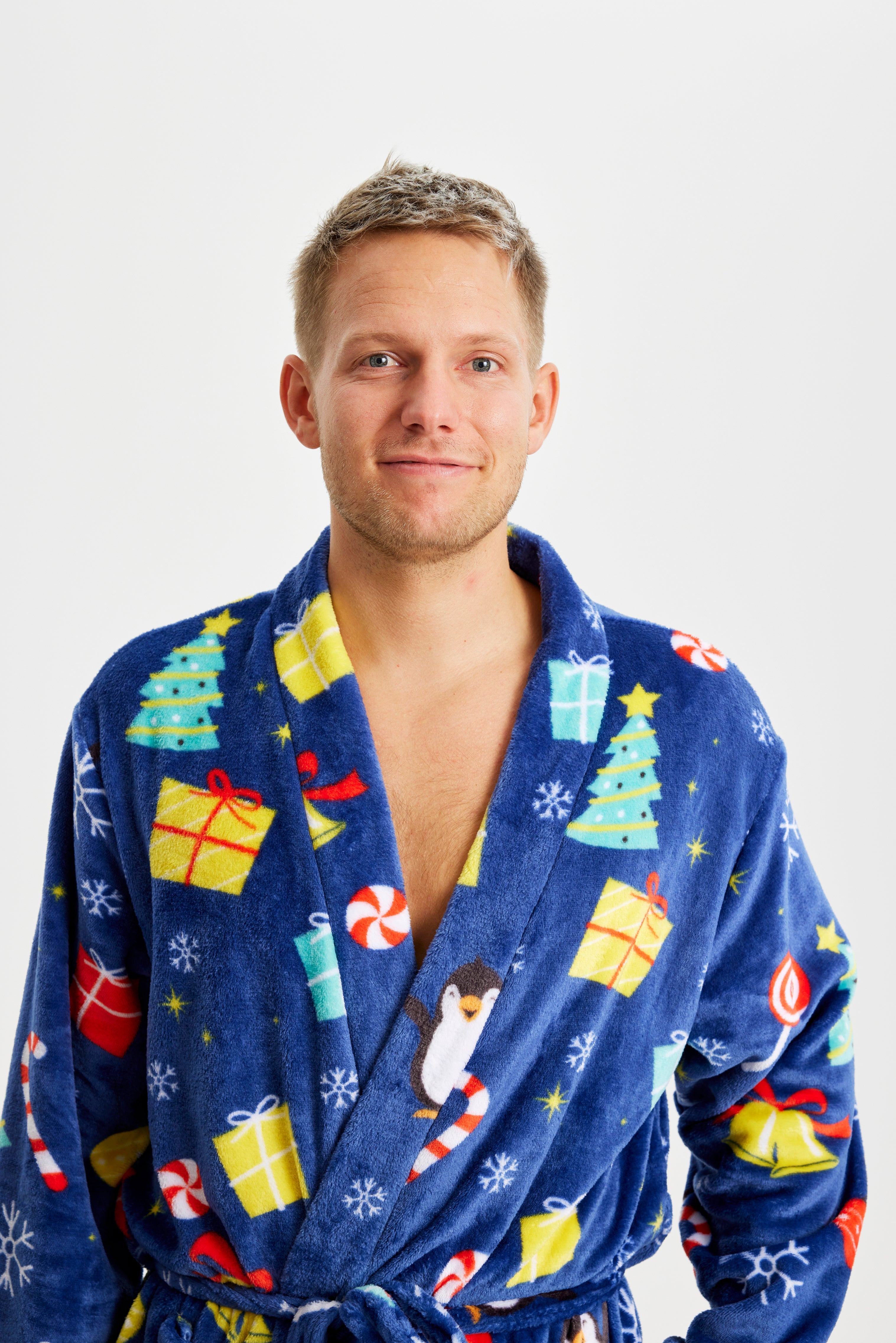 Ein Mann, der einen blauen Weihnachtsbademantel mit einem Weihnachtsmuster trägt.
